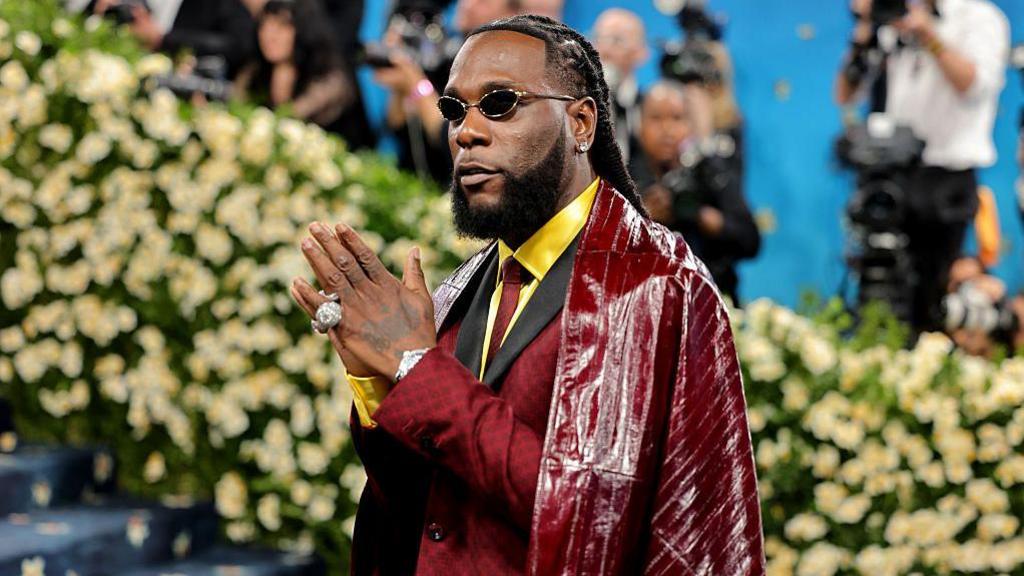Burna Boy poses on the Met Gala red carpet, wearing the suit and cape Ozwald Boateng made for him