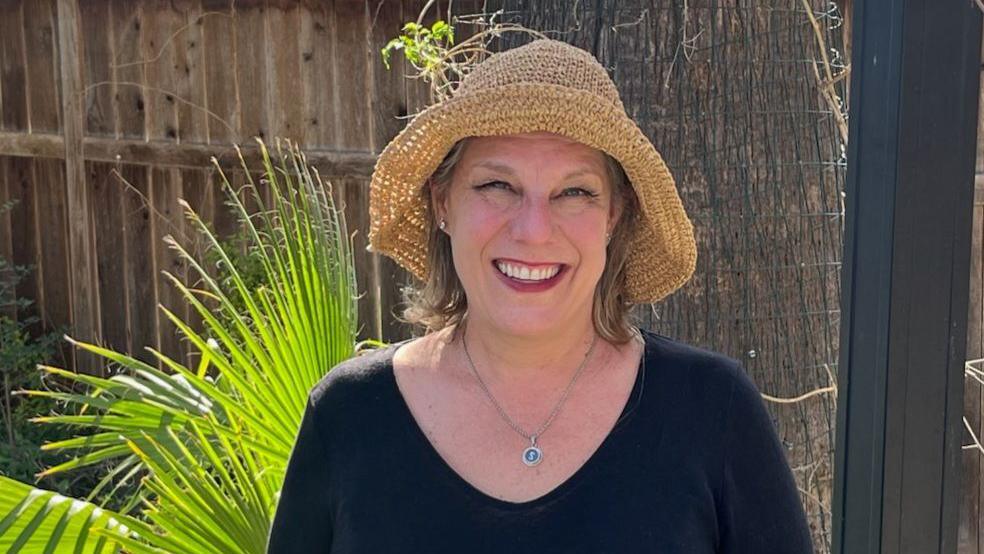 Sierra Hanson wearing a straw hat and standing in front of a fern.