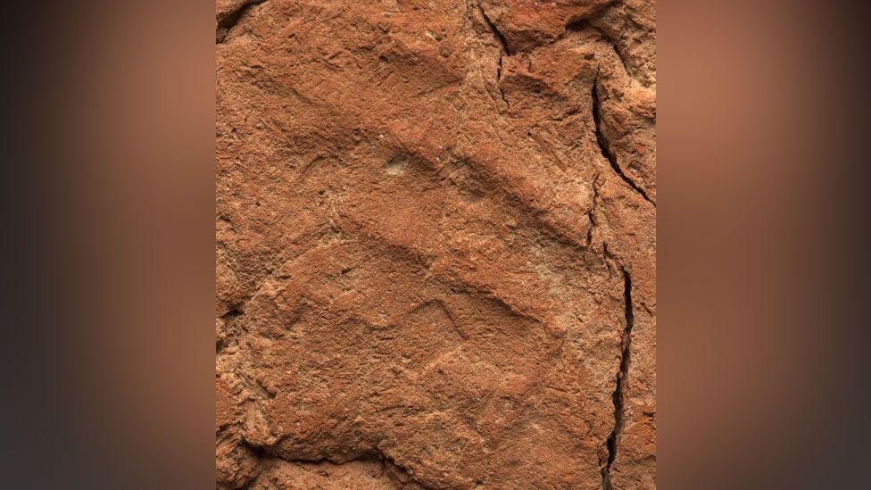 A close-up of the base of the ancient Egyptian soul house made of lumpy light brown clay. The close up shows three ridges made by finger marks. They run from the top left corner to the bottom right corner. 